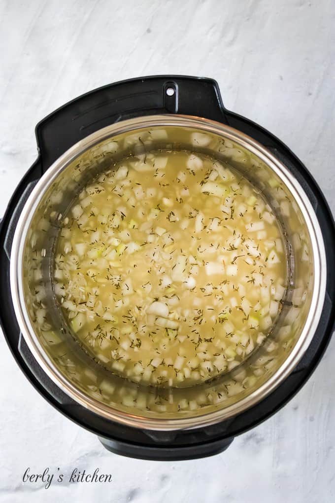 Onions, garlic, and other ingredients in the pressure cooker liner.