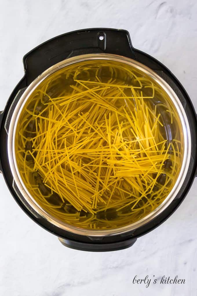 The dry spaghetti stacked inside of the pressure cooker liner.