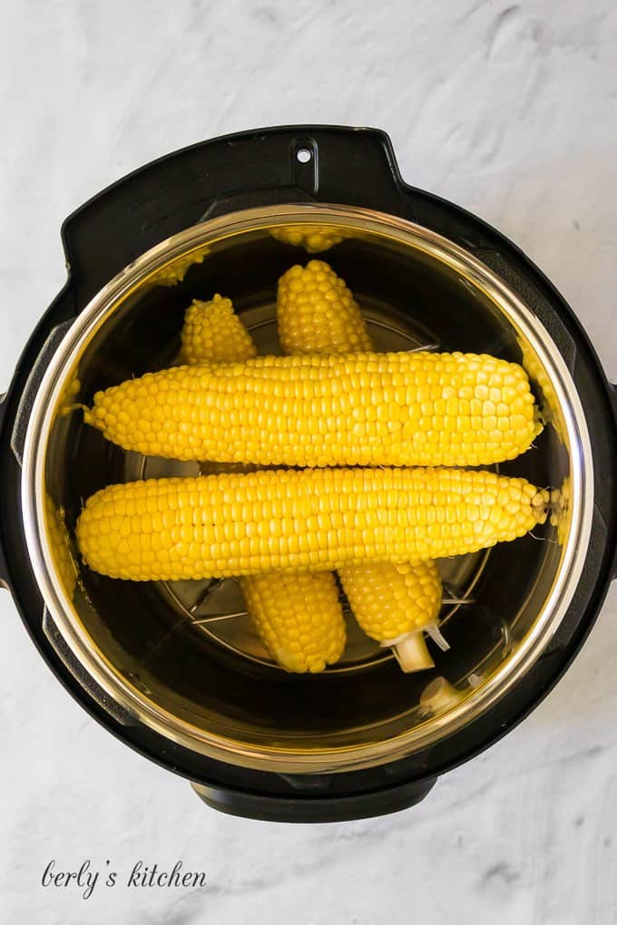 The ears have been stacked horizontally inside the pressure cooker.