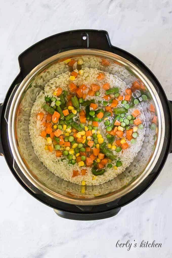 The frozen vegetables have been placed on top of the rice.