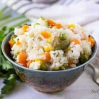 A decorative bowl filled with the pressure cooker rice with vegetables.