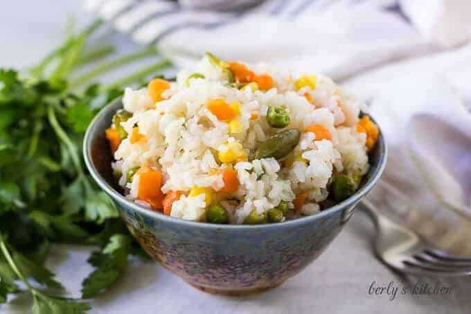 A decorative bowl filled with the pressure cooker rice with vegetables.