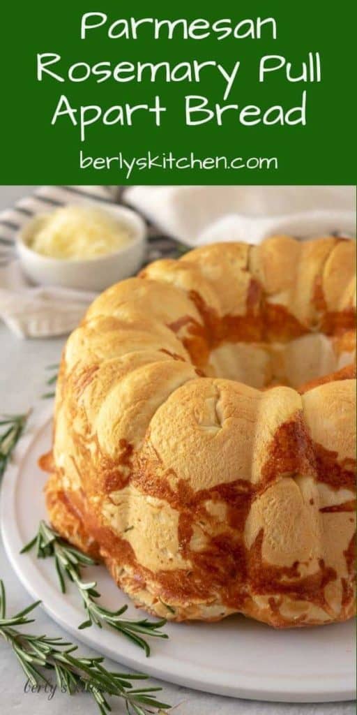 The Parmesan rosemary pull apart bread on a plate with herbs.