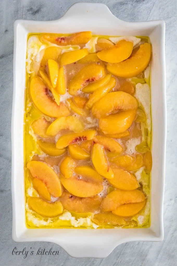 The peaches have been laid on top of the batter.
