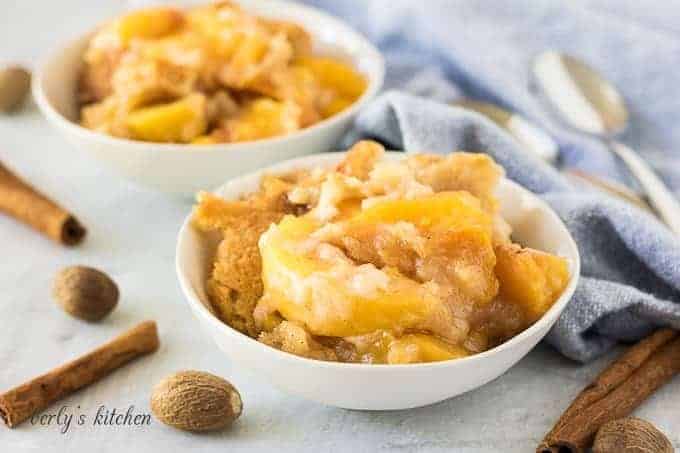 Two small bowls of the easy peach cobbler accented with fresh spices.