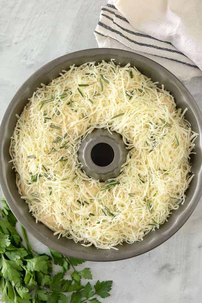 A bundt pan showing the layers of dough, herbs, and cheese.