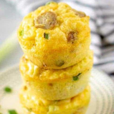 Sausage Cheese And Egg Muffin Cups Three sausage egg and cheese muffin cups stacked on a plate.