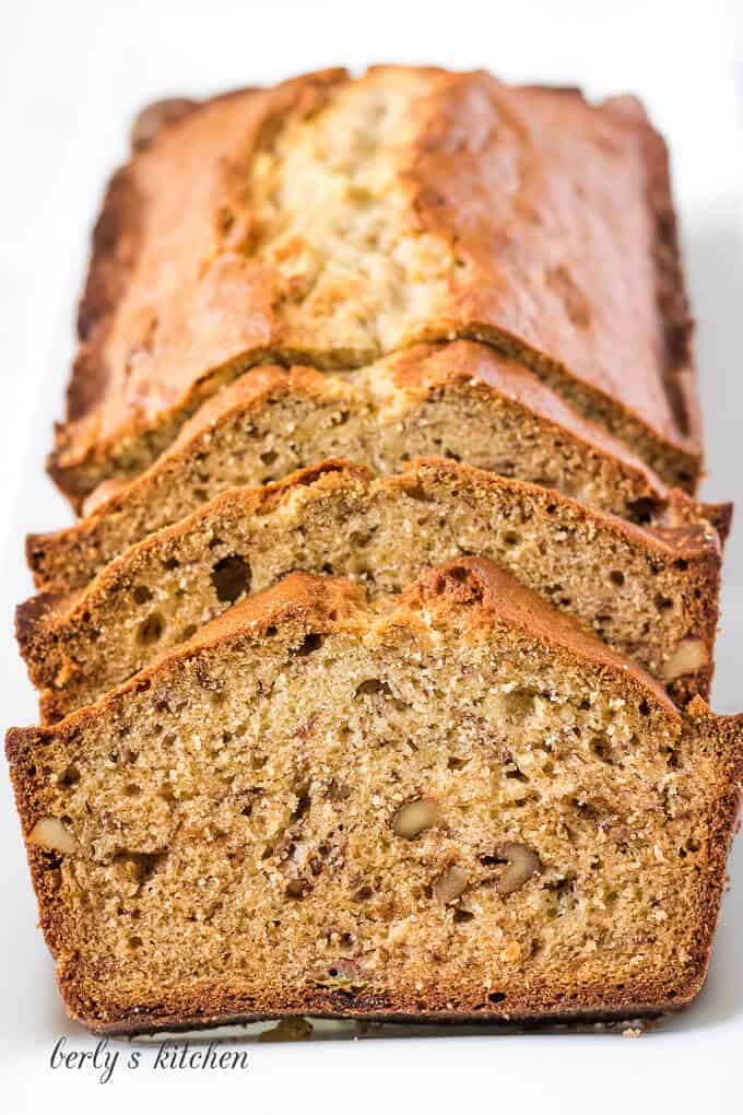 Front facing photo of a loaf of sliced banana bread on a white platter.