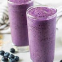 Two large glasses of the blueberry smoothie surrounded by berries.