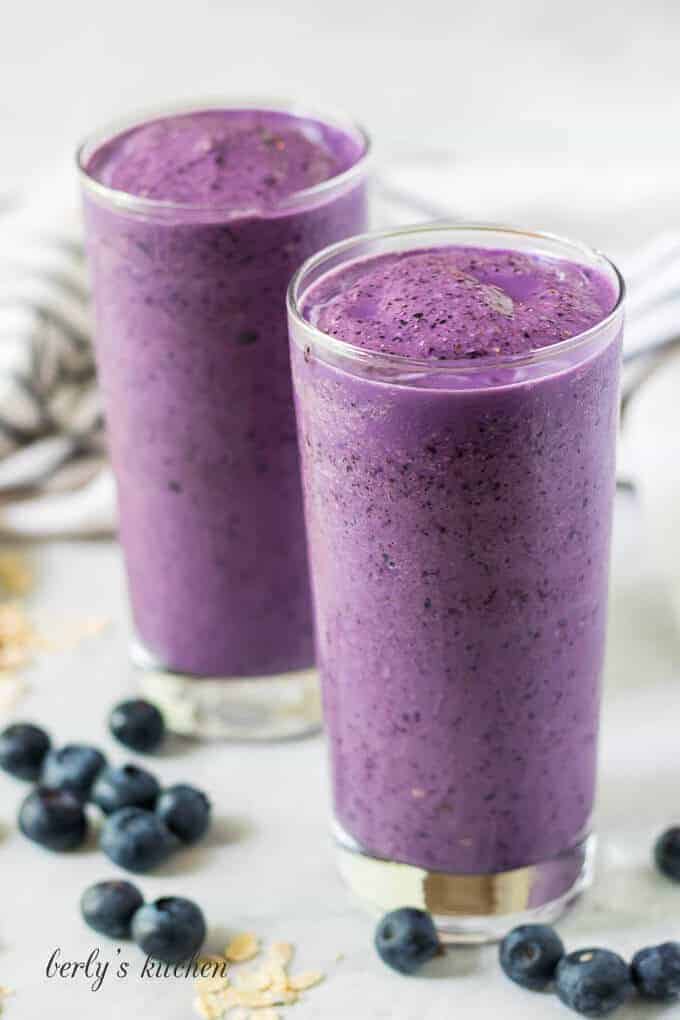 Two large glasses of the blueberry smoothie surrounded by berries.