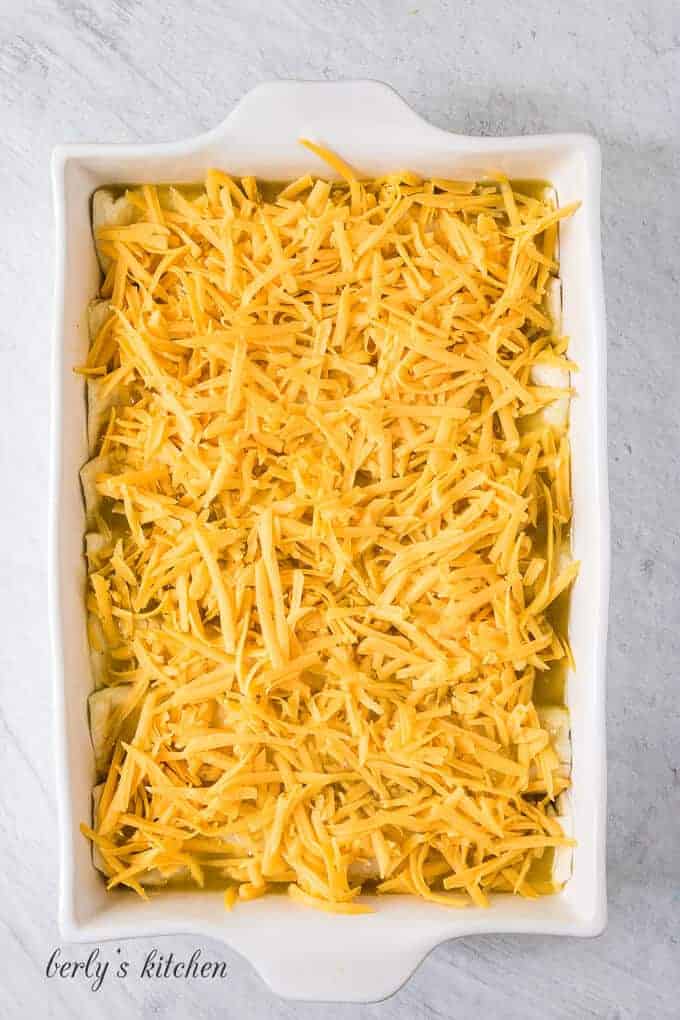 The green sauce has been topped with shredded cheddar cheese.