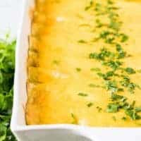 The baked cheesy enchiladas garnished with fresh chopped parsley.