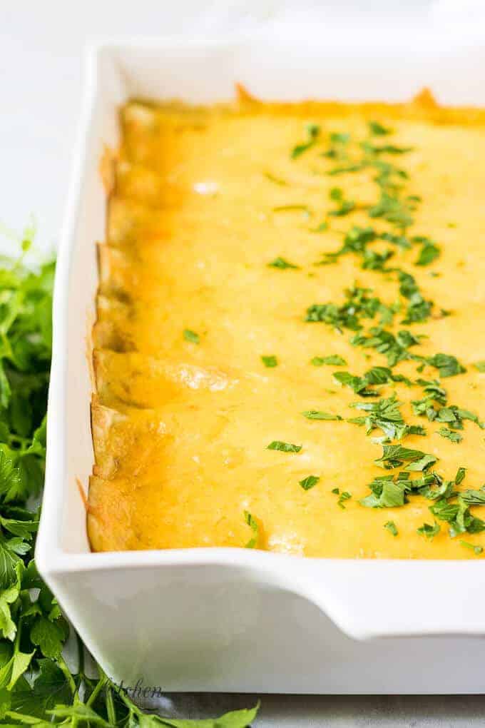 The baked cheesy enchiladas garnished with fresh chopped parsley.