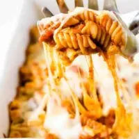 The baked cheesy pasta being scooped out of the dish.