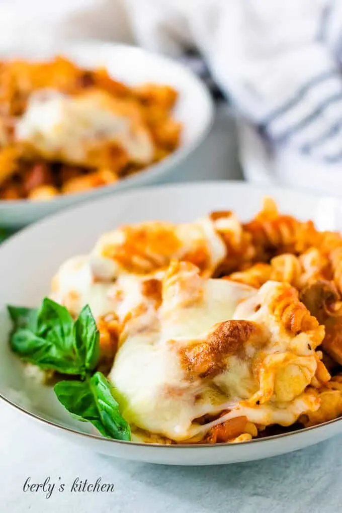 Two bowls of the pasta casserole garnished with fresh basil.