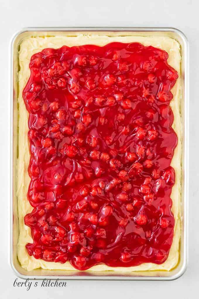 Batter and cherry pie filling layered in a jelly pan.