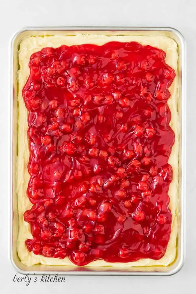 Batter and cherry pie filling layered in a jelly pan.