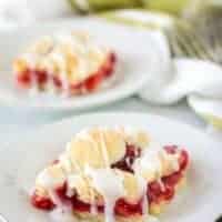 Two cherry bars, topped with almond icing, served on plates.