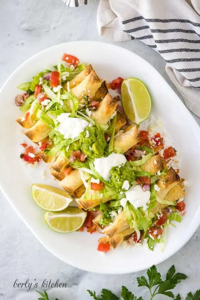 An aerial view of the taquitos with toppings like lettuce and guacamole.