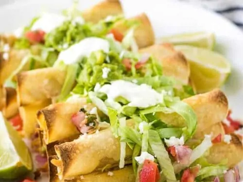 The baked chicken taquitos topped with lettuce, tomatoes, and guacamole.