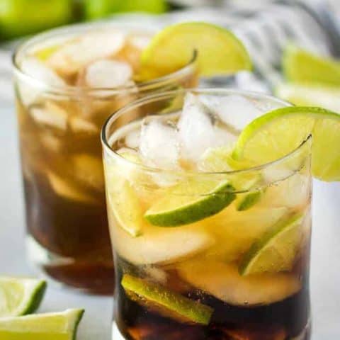 The cuba libre drink has been garnished with a lime wedge.