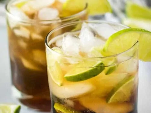 The cuba libre drink has been garnished with a lime wedge.