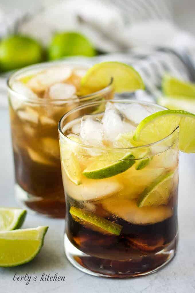 The cuba libre drink has been garnished with a lime wedge.