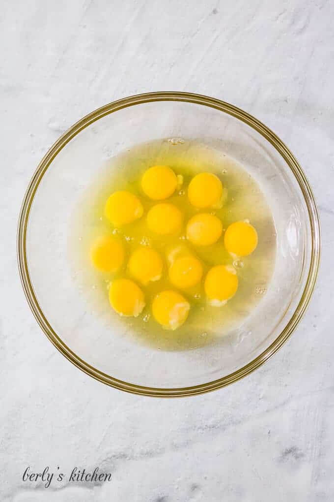 Twelve large cracked eggs in a mixing bowl for mixing.