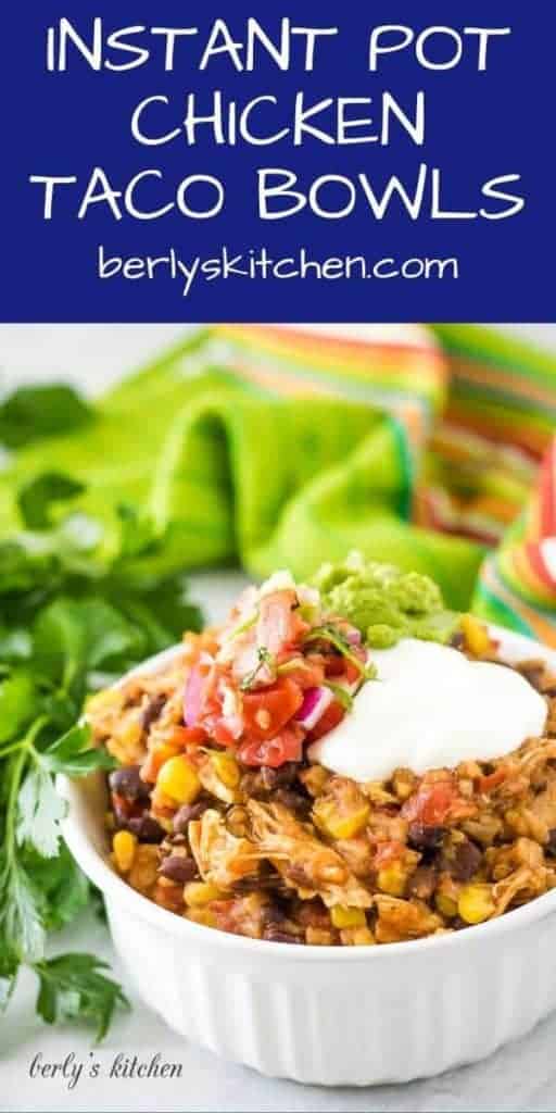 A chicken taco bowl topped with guacamole, salsa, and sour cream.