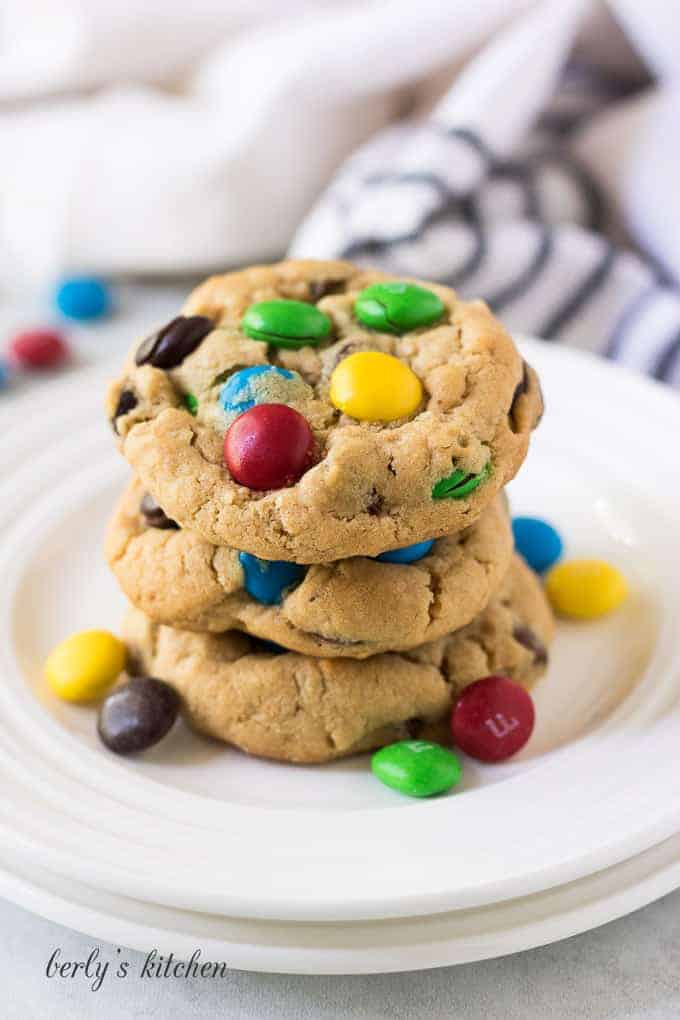 A stack of cookies on a white plate with candy.