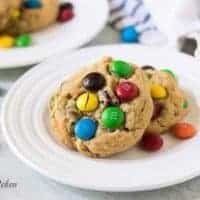 Two monster cookies on a plate with colorful chocolate candies.