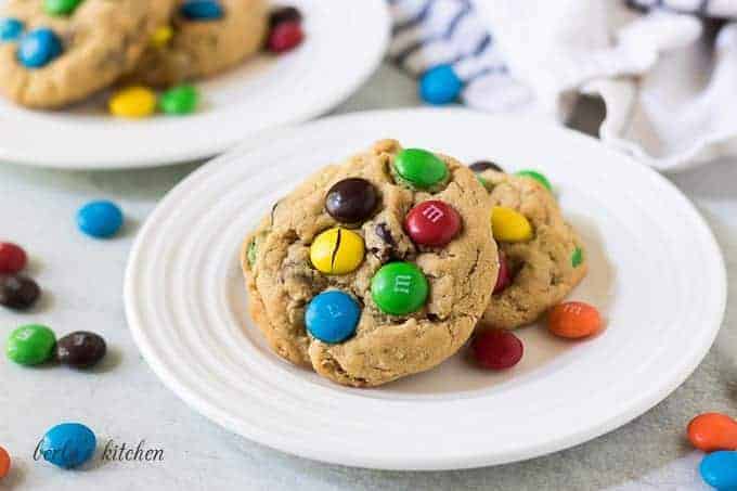 Two monster cookies on a plate with colorful chocolate candies.