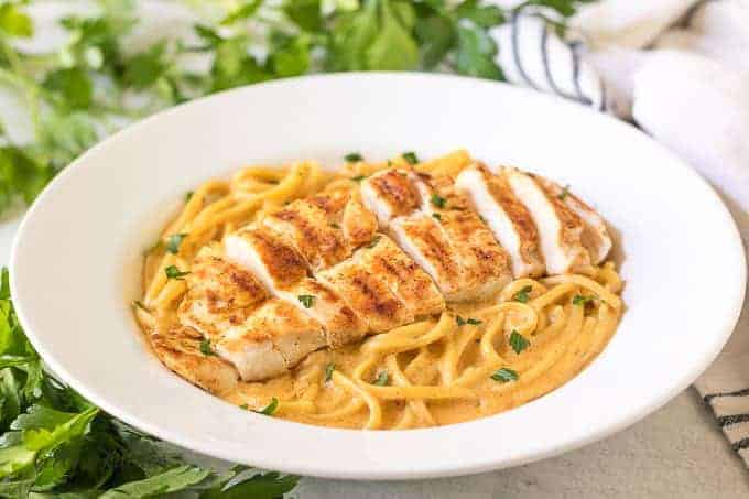 The spicy chicken pasta in a bowl garnished with parsley.