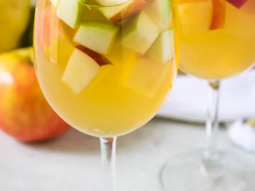 The finished apple sangria poured into two white wine glasses.