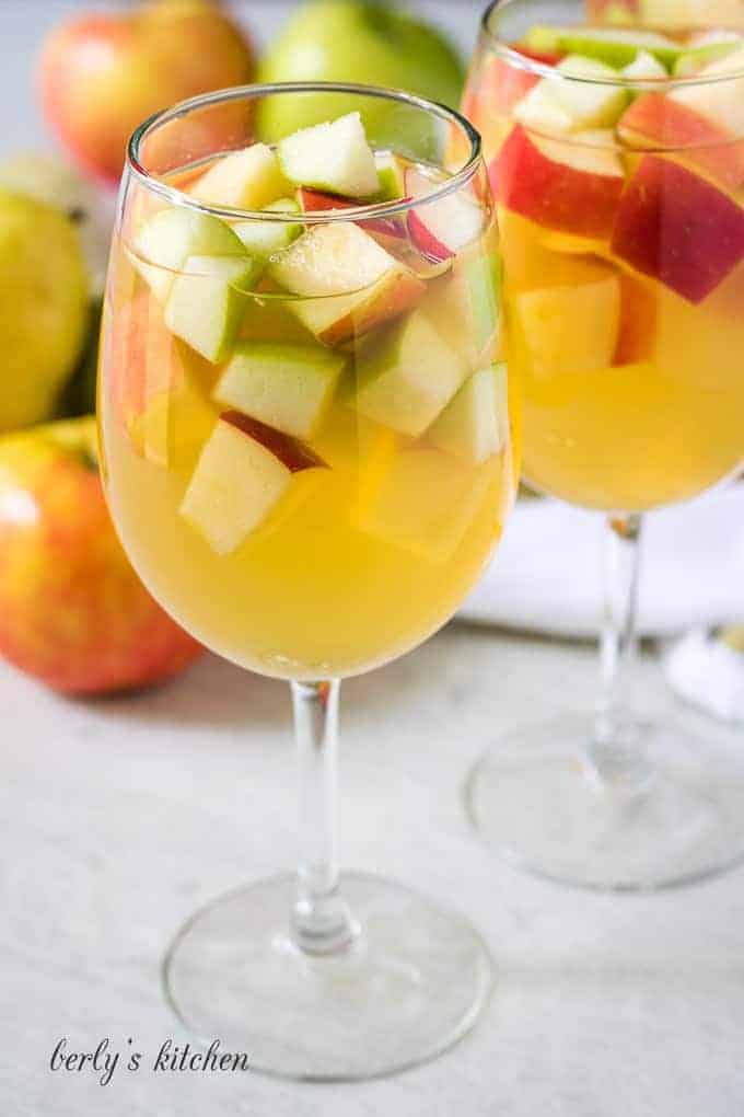 The finished apple sangria poured into two white wine glasses.