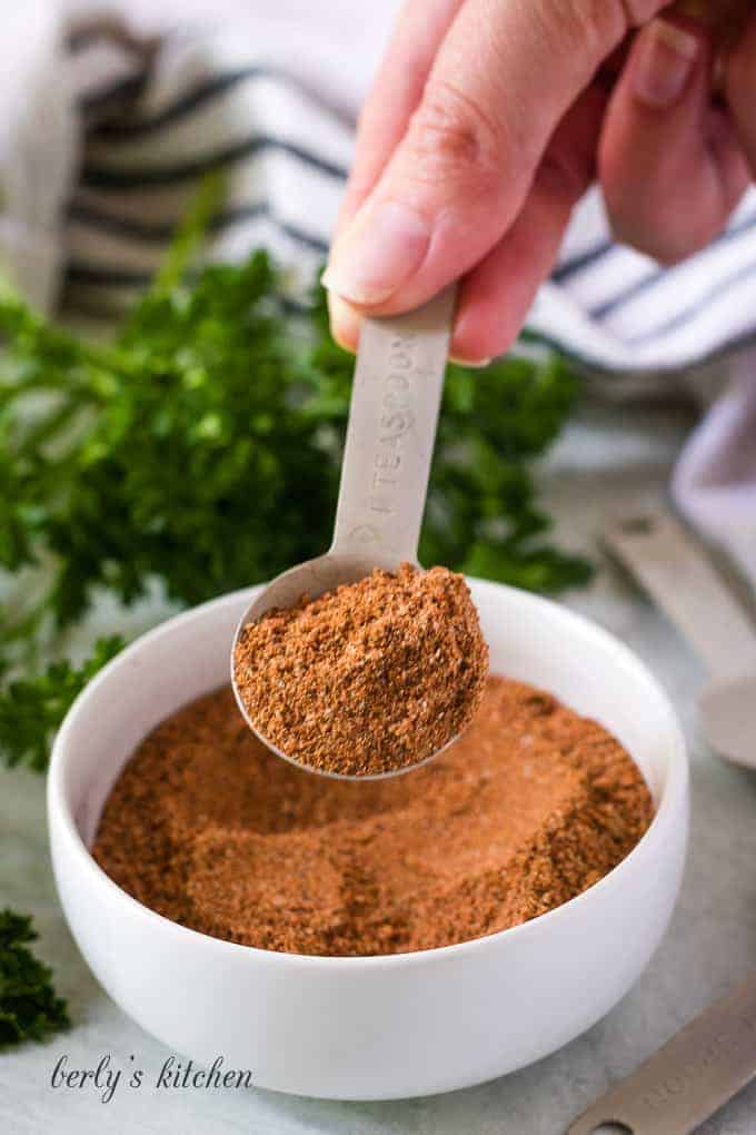 The fajita seasoning mix being lifted from the small bowl.