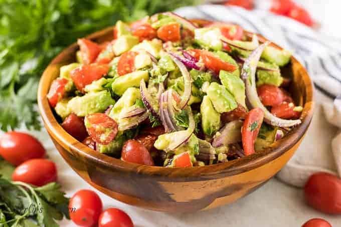 The tomato avocado salad in a wooden bowl.