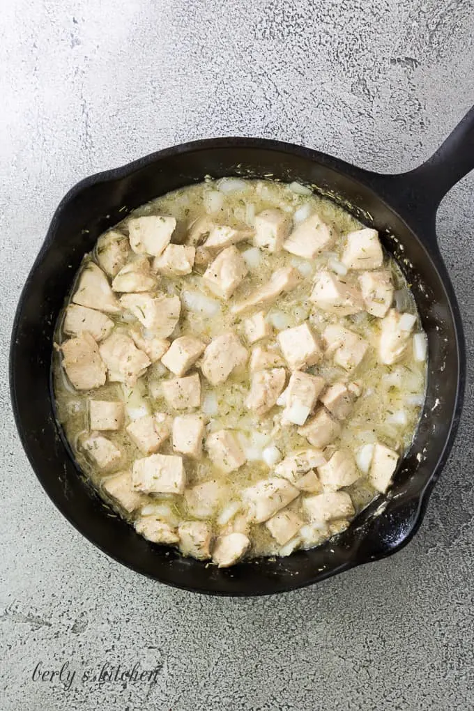 Butter, meat, and seasonings cooking in a cast iron skillet.