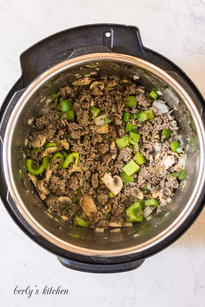 Ariel view of meat, peppers, and onions in the liner of an instant pot.