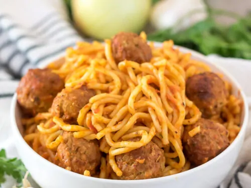 The spaghetti with meatballs served in a decorative white bowl.