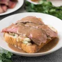 Leftover pot roast atop mashed potatoes and bread topped with gravy.