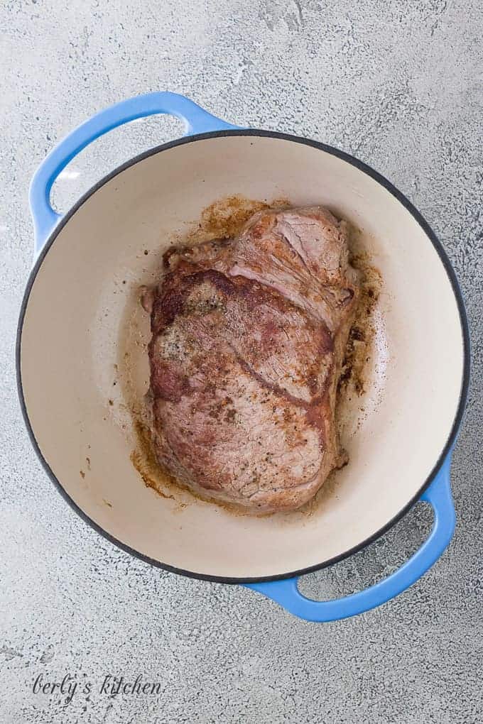 The pot roast being seared in a hot Dutch oven.