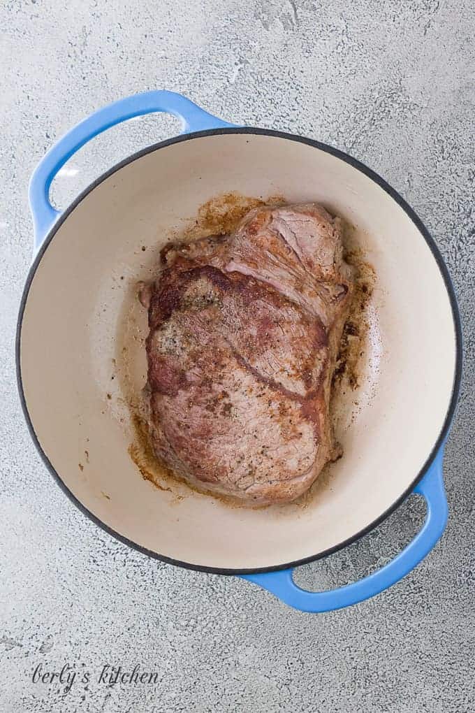 The pot roast being seared in a hot dutch oven.