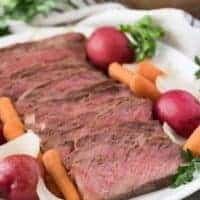 The finished roast on a serving platter with cooked vegetables.