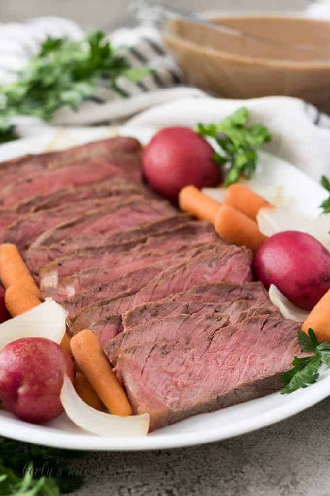 The finished roast on a serving platter with cooked vegetables.