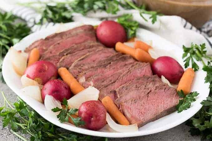 The finished roast sliced and surrounded by potatoes and carrots.