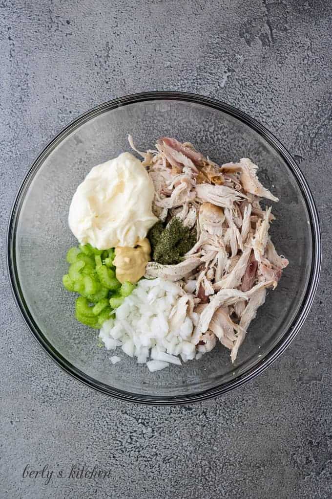 Turkey, mayo, and other ingredients in a glass mixing bowl.