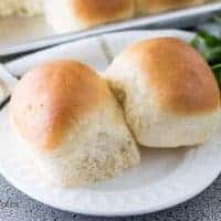 Two yeast rolls topped with butter on a decorative saucer.