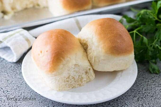 Two yeast rolls topped with butter on a decorative saucer.