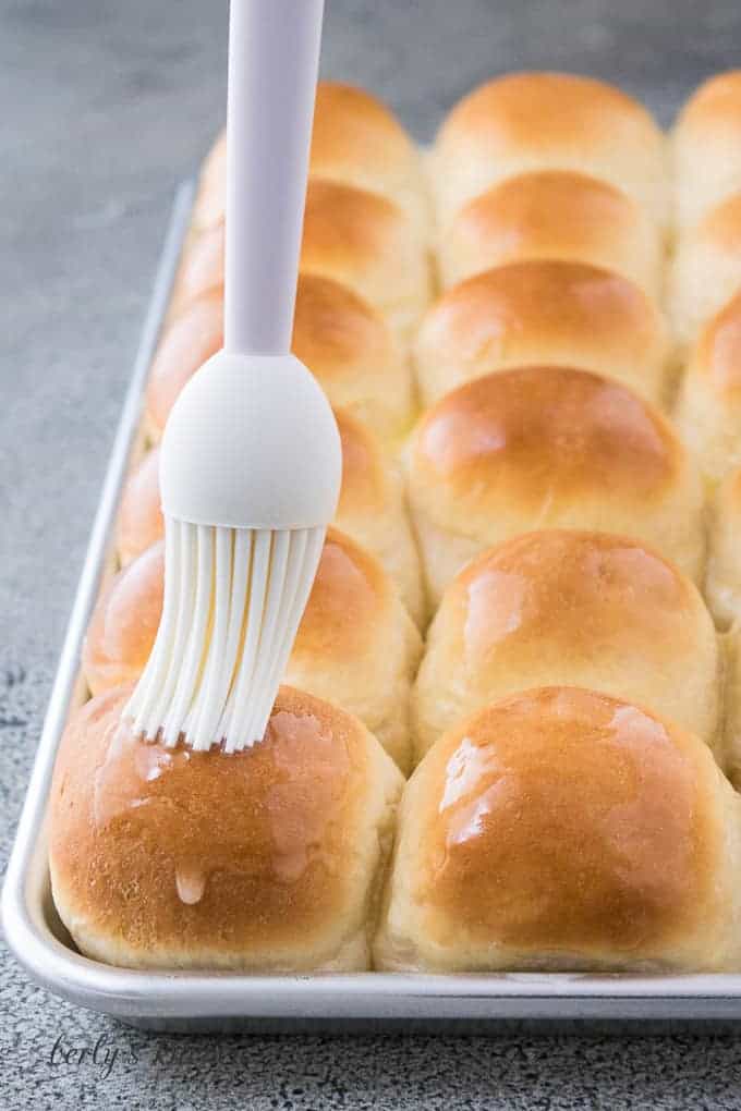 A basting brush topping the bread rolls with melted butter.